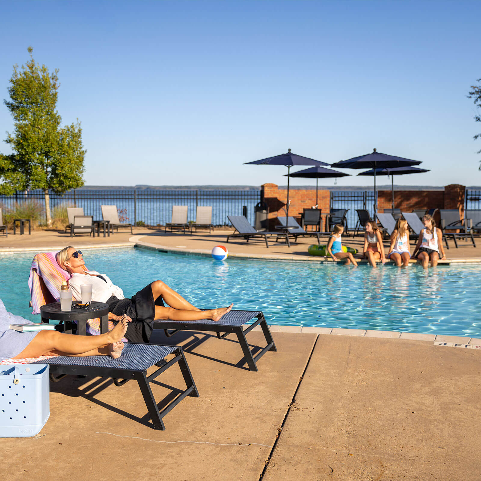 People sit and lounge beside The Town of Lost Rabbit's community pool.